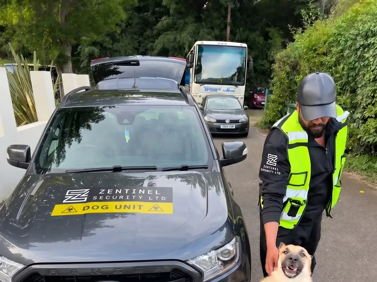 Zentinel dog unit handler with security dog beside branded vehicle